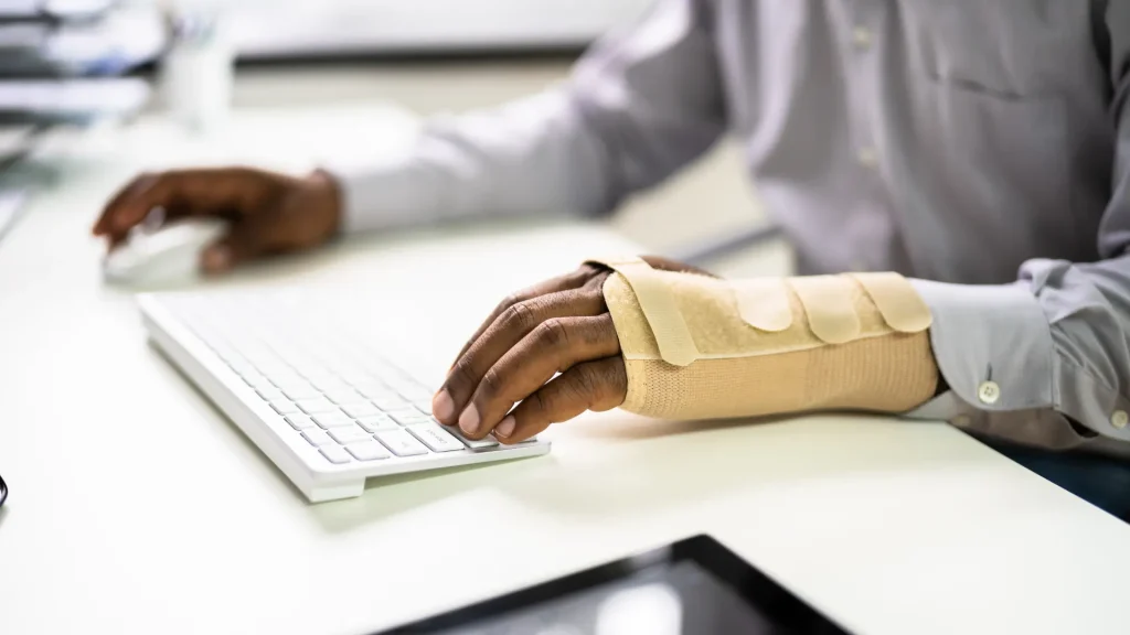 A person wearing a beige wrist brace typing on a keyboard.