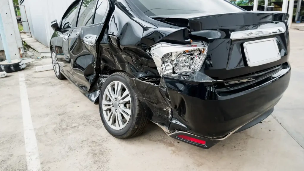 Severely damaged black car with crumpled rear side after an accident.