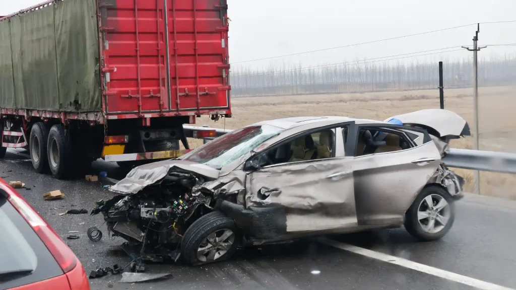 Severely damaged car after a collision with a large red truck.